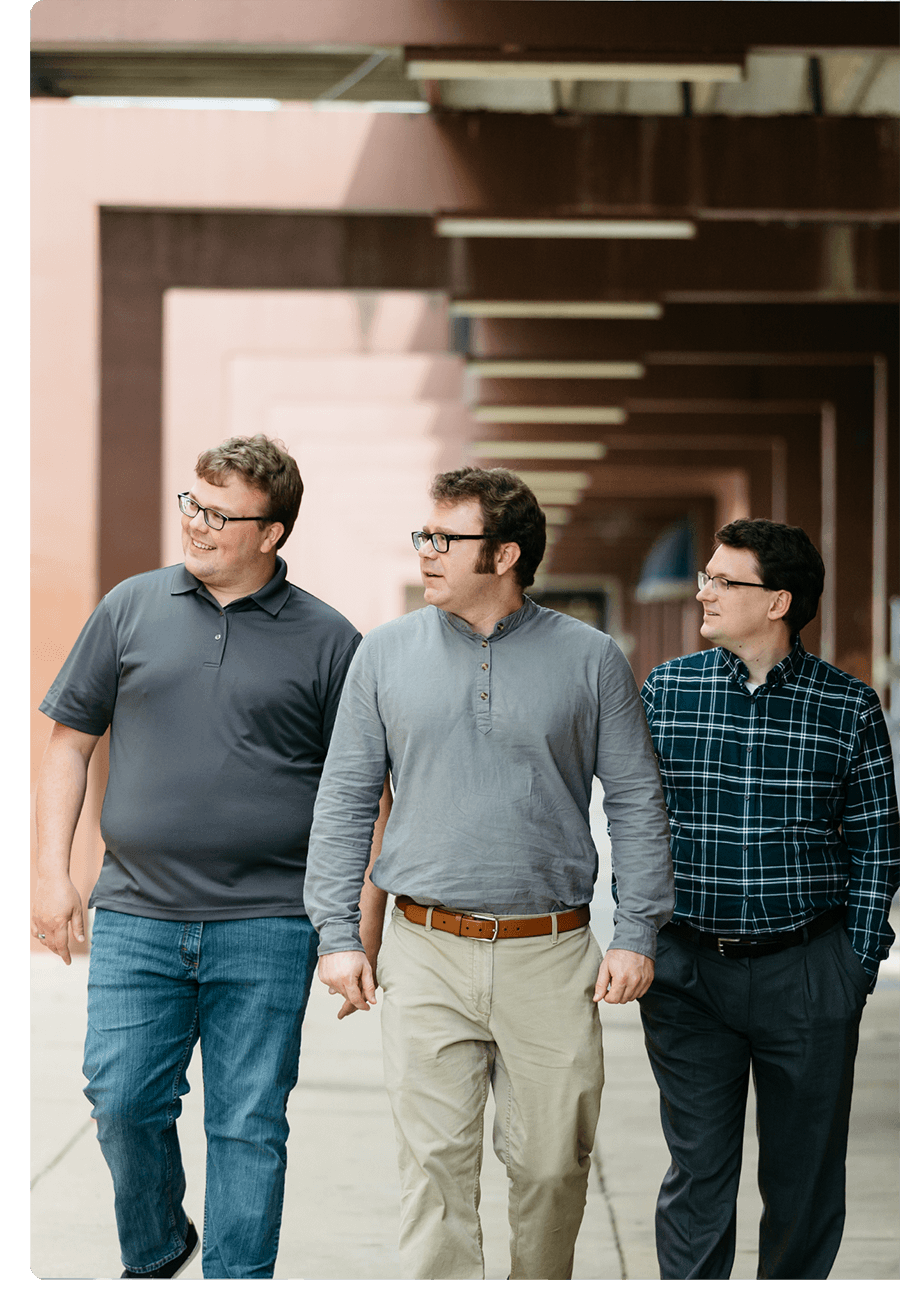 Three men walking downtown on a sidewalk.